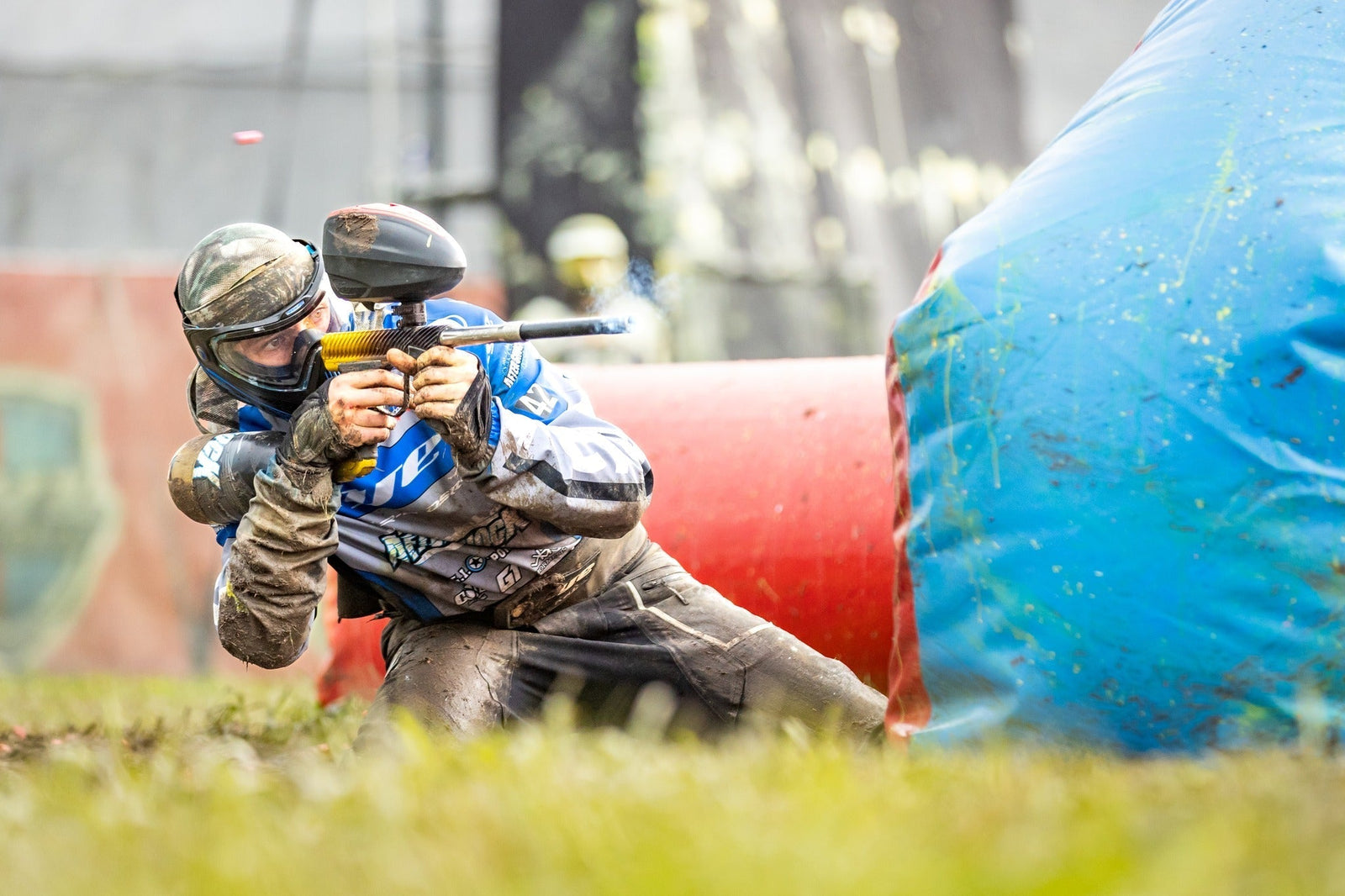 Paintball-Spieler kniet auf Boden des Spielfelds.